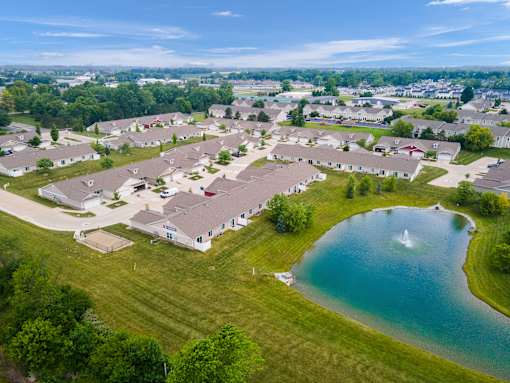 A bird's eye view of a residential area with houses surrounding a pond.