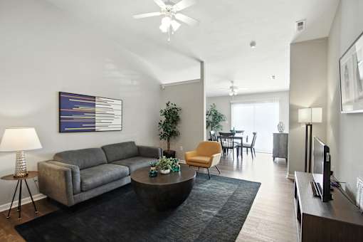 A living room with a grey couch, a yellow chair, a black coffee table, and a painting on the wall.