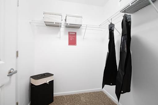 A small closet with a red sign on the wall and two coats hanging up.