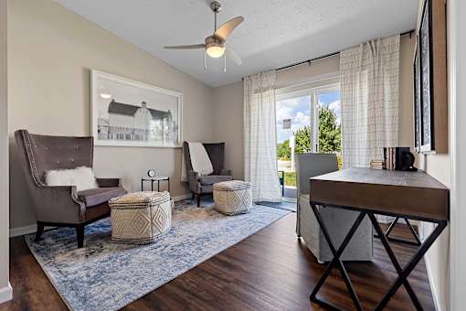 A living room with a brown chair and ottoman, a white armchair, and a wooden coffee table.