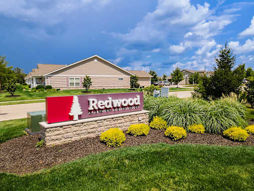 A sign for Redwood Apartment Homes is in front of a building.