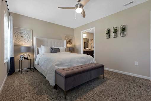 A bedroom with a large bed and a ceiling fan.