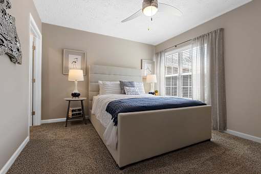 A bedroom with a large bed and a ceiling fan.