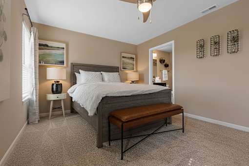 A bedroom with a bed, nightstand, and a bench.