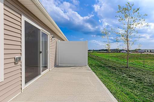 A house with a sliding glass door and a concrete walkway leading to it.