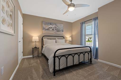 A bedroom with a large bed and a ceiling fan.