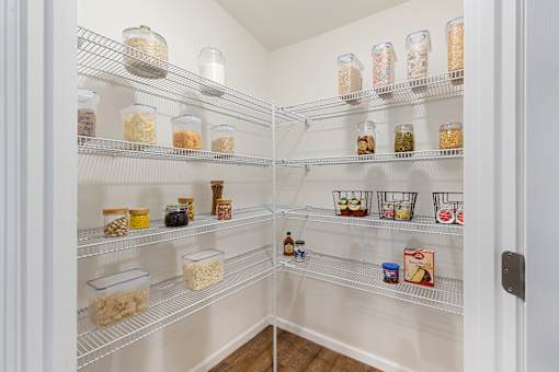 A pantry with a white door and shelves filled with jars and containers.