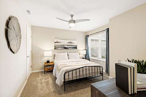 A bedroom with a bed, nightstands, and a ceiling fan.