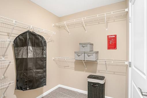 A walk-in closet with a black coat hanging on a rod.