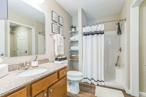 A bathroom with a white toilet, sink, and shower.