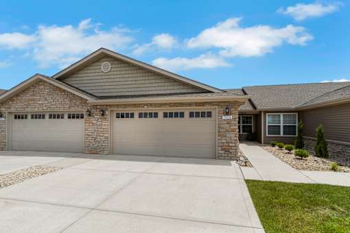 A house with a grey garage door and a stone pillar.