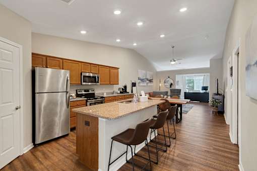 A kitchen with a refrigerator, stove, and bar area.