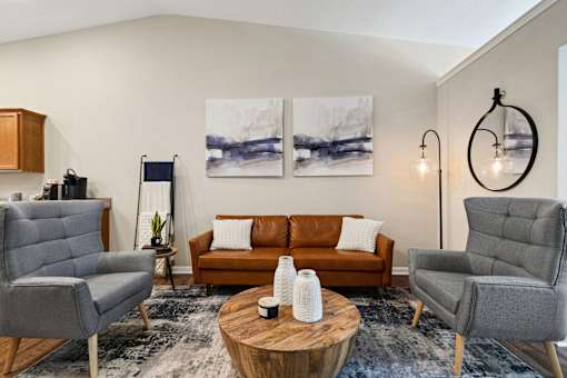 A living room with a brown couch, grey armchairs, and a wooden coffee table.