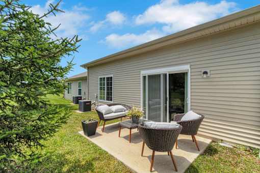 A patio with a table and chairs is in front of a house.