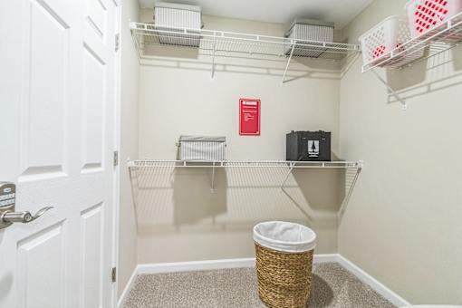 A white door is open to a small closet with a basket on the floor.