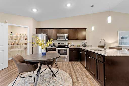 A kitchen with brown cabinets and a round table with chairs.