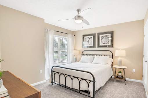 A bedroom with a bed, nightstand, and a ceiling fan.