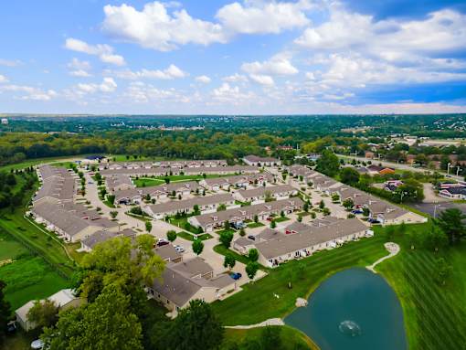 A bird's eye view of a residential area with houses, a lake, and a road.