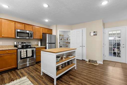 A kitchen with wooden cabinets and a white island.