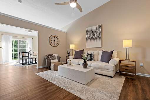 A living room with a white couch, a coffee table, and a ceiling fan.