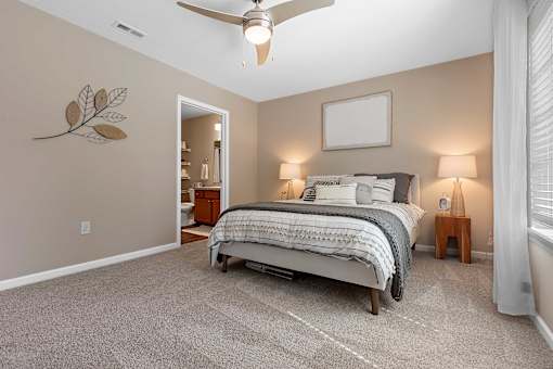 A bedroom with a large bed, a ceiling fan, and a leaf-shaped decoration on the wall.