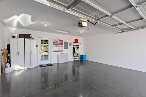 A spacious room with a grey floor and white walls, equipped with a ceiling lighting system and a few cabinets.