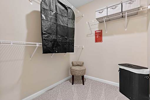 A baby crib sits in a room with a chair and a hanging closet.