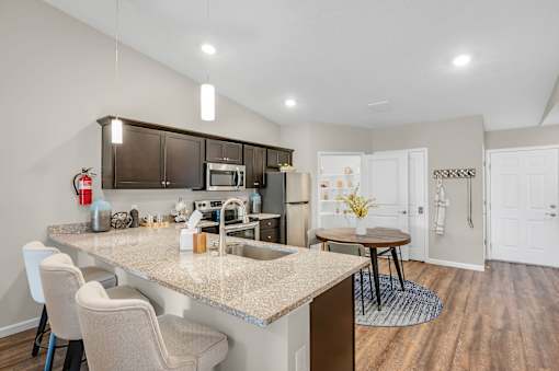 A kitchen with a table and chairs in front of a sink.