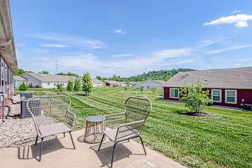 A patio with two chairs and a table is in front of a house.