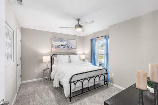 A bedroom with a large bed and a painting on the wall.
