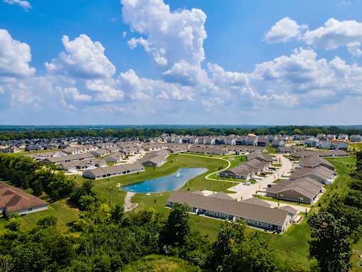 A bird's eye view of a residential area with houses, a swimming pool, and a winding road.