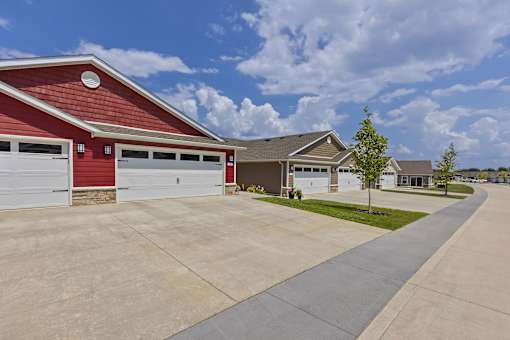 A red building with a white garage door is in front of a house.
