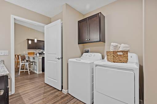 A laundry room with a washer and dryer and a basket of towels.