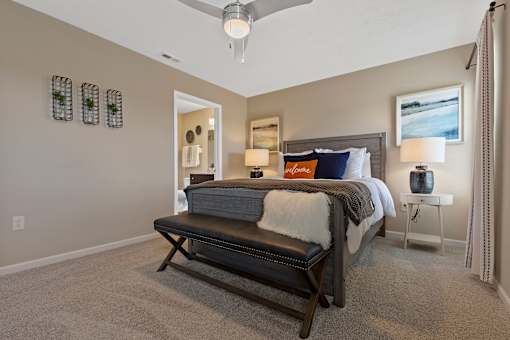 A bedroom with a bed, bench, and a ceiling fan.
