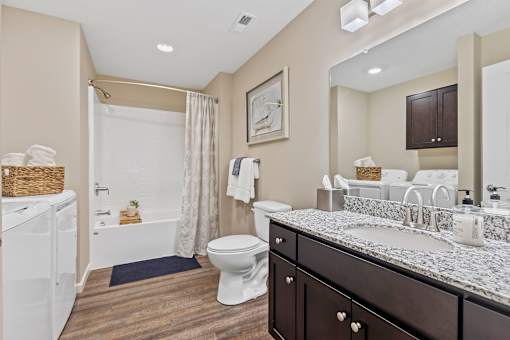 A bathroom with a white toilet, a white bathtub, a sink, and a mirror.