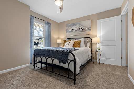 A bedroom with a bed, nightstand, and a painting on the wall.