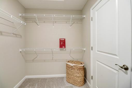 A small white closet with a basket and a red sign on the shelf.