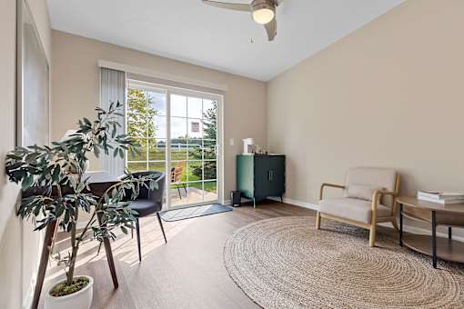 A room with a chair, a table, a potted plant, and a rug.