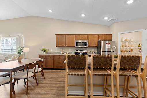 A kitchen with brown chairs and wooden cabinets.