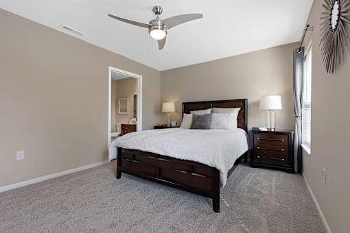 A bedroom with a bed, nightstands, and a ceiling fan.