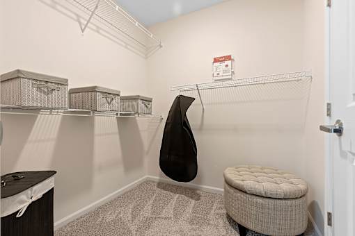 A room with a bench, a coat rack and a door.