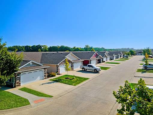 A residential street with houses on both sides and cars parked in front.