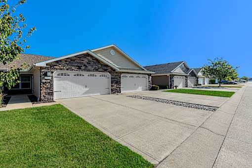 A house with a stone wall and two garages.
