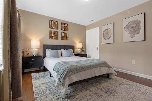 A bedroom with a bed, nightstand, and pictures on the wall.