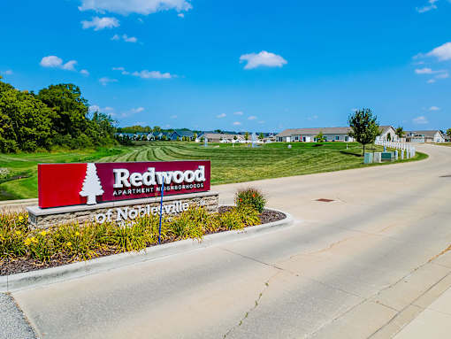 A sign for Redwood Apartment Homes sits in front of a road.