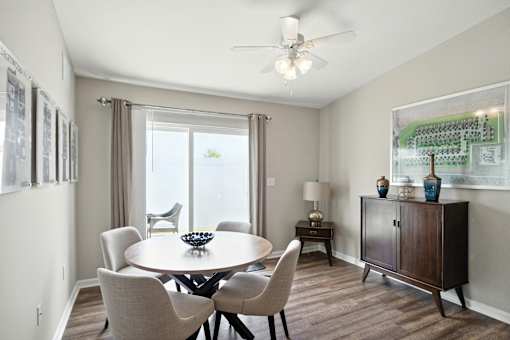 A dining room with a table, chairs, and a ceiling fan.