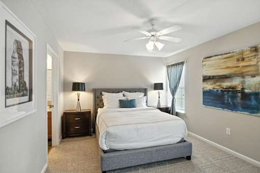 A bedroom with a large bed and a ceiling fan.