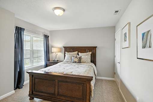 A bedroom with a large bed and a painting on the wall.