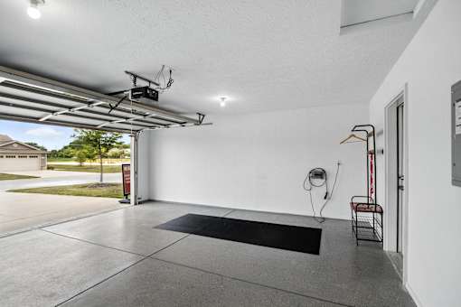A garage with a black mat on the floor and a red fire extinguisher on the wall.