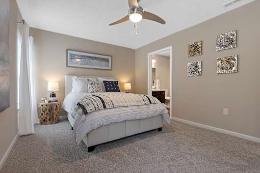 A bedroom with a large bed and a ceiling fan.